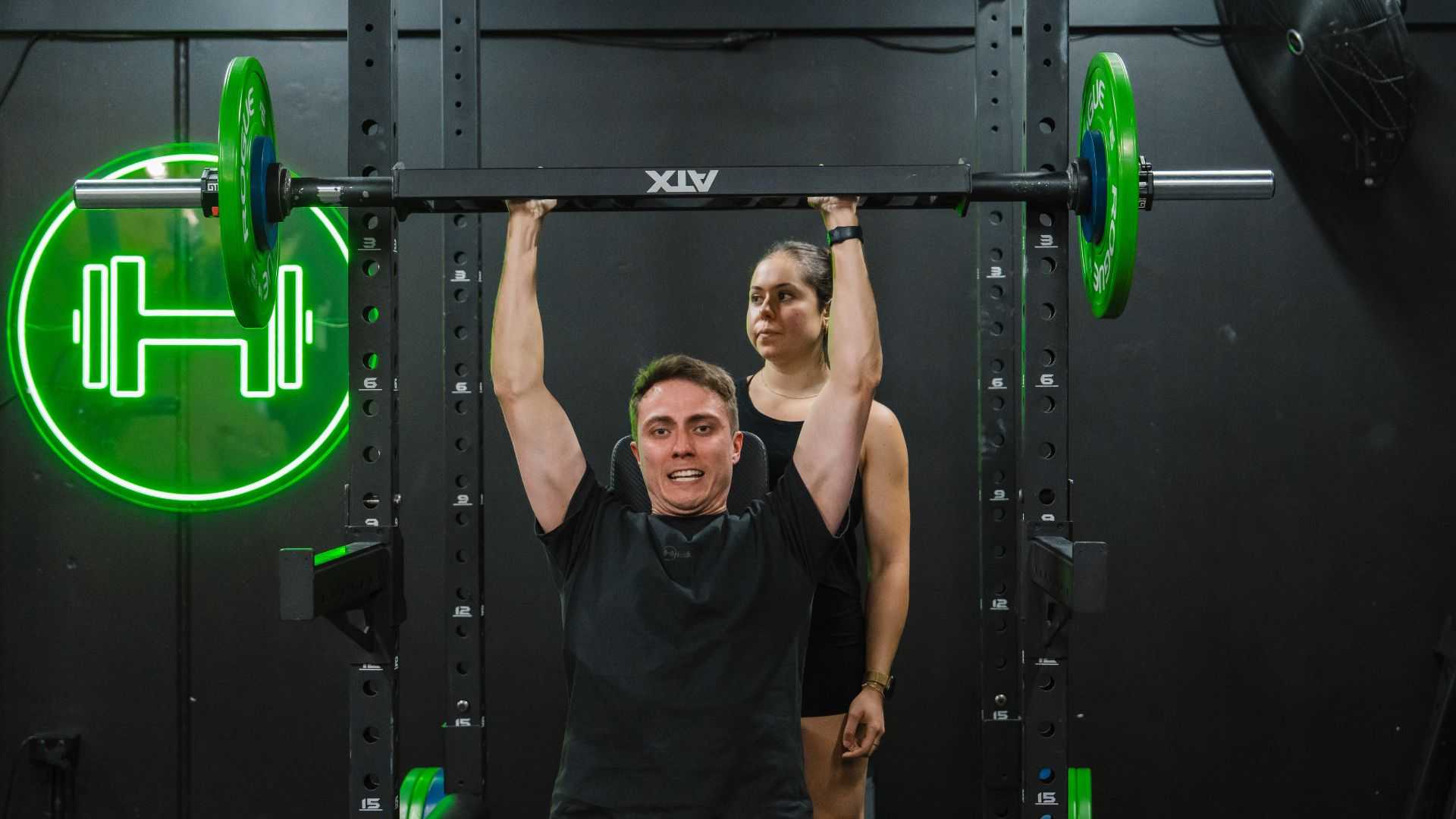 Personal trainer coaching a client in the gym, helping him with form and technique.