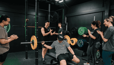 Coach and gym members cheering for a person doing bench press