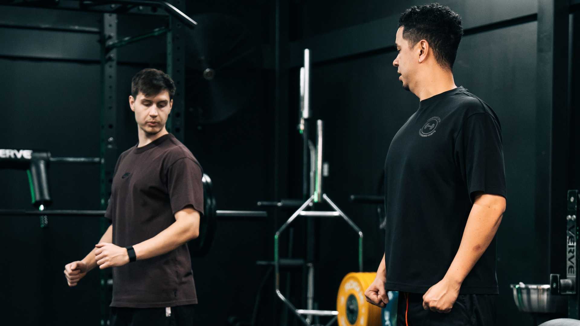 Personal trainer guiding a client during a strength training session in the gym, focusing on form and technique.