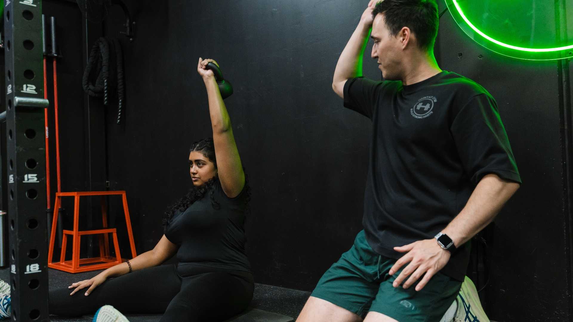 Personal trainer coaching a client in the gym, helping him with form and technique.