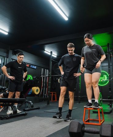 Trainer observing female member’s fitness form in Habitat Gym's strength zone