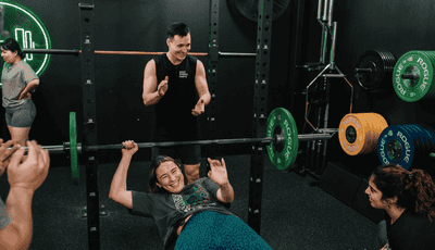 Member having fun whilst bench pressing inside Habitat Gym’s private training facility in Prestons