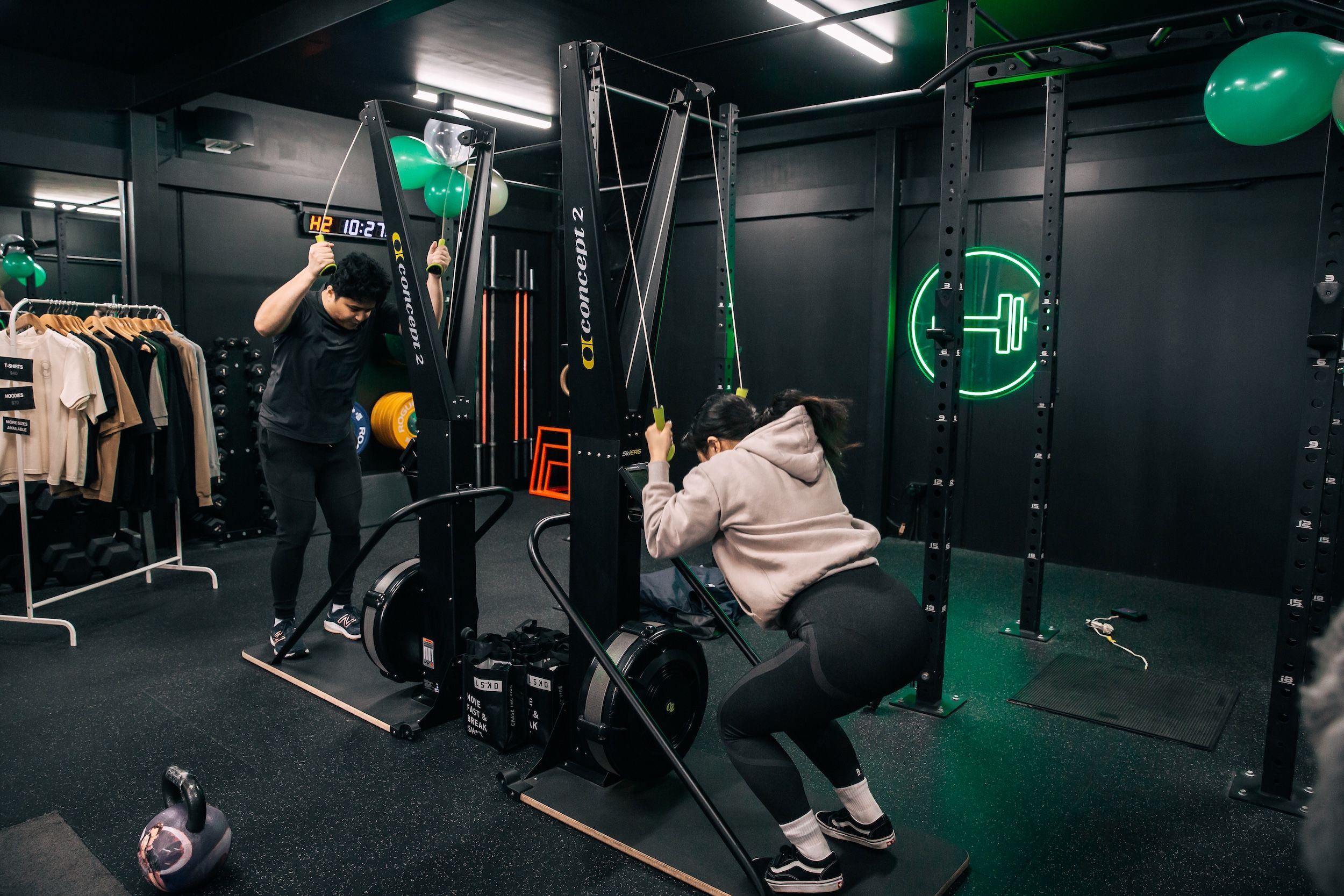 Two gym members inside Habitat Gym Prestons training on the ski erg