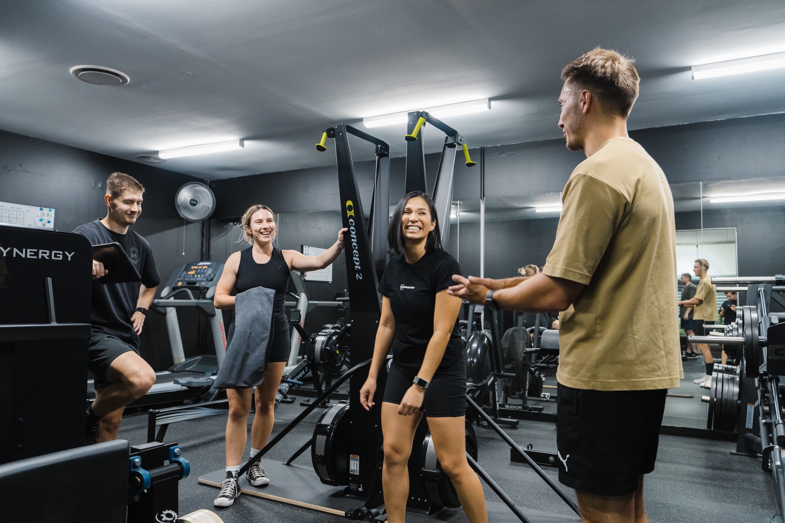 Coach and three gym members sharing a laugh between exercises at Habitat Gym Prestons