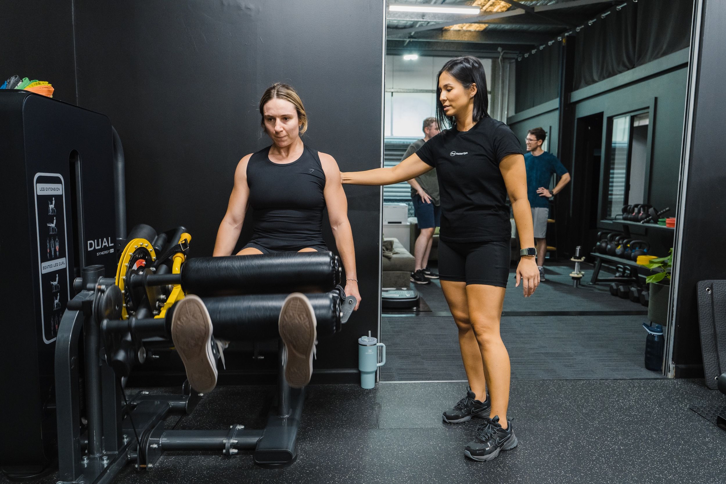 Co-founder of Habitat Gym, Jeannie assisting client on leg press machine while in their semi-private personal training session in Prestons