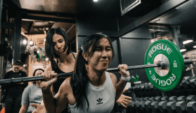 Coach Jeannie spotting a gym member during a weightlifting session at Habitat Gym