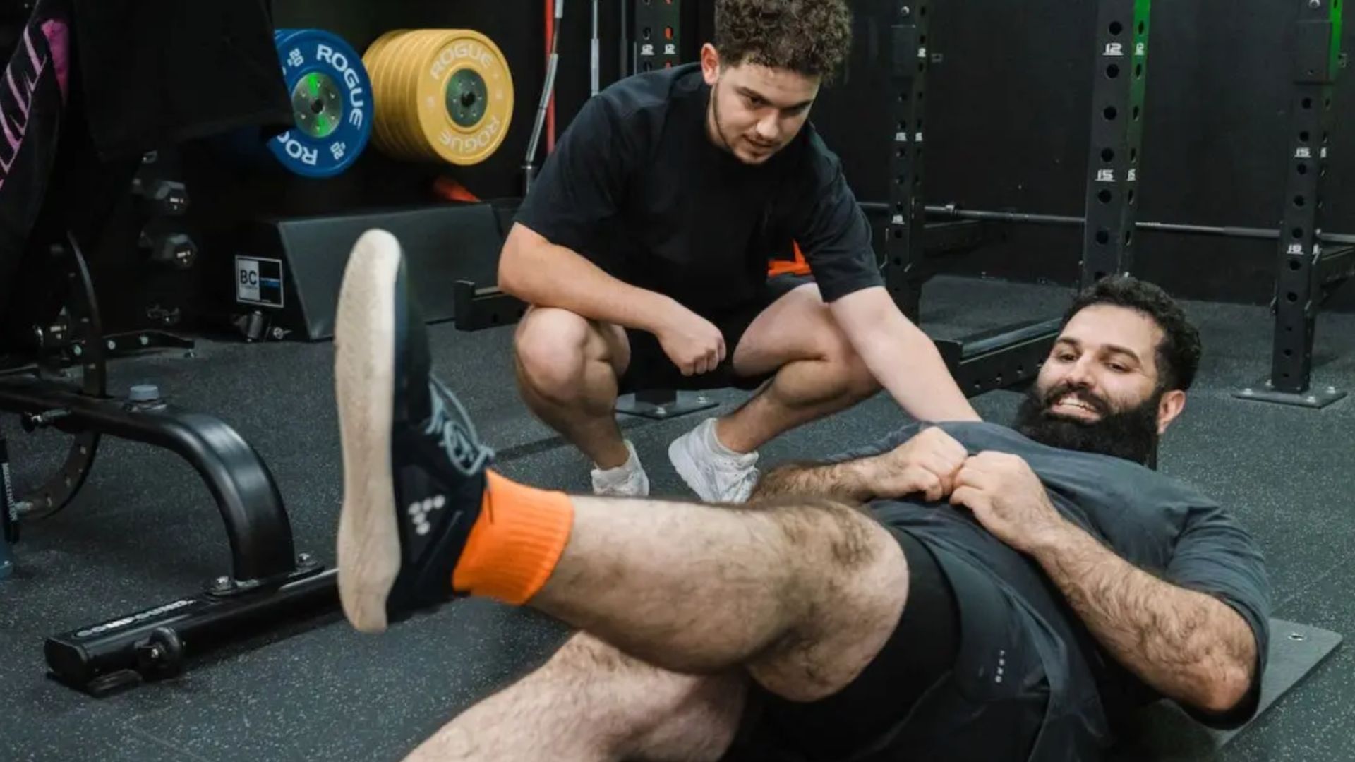 Personal trainer coaching a client through a floor core exercise, focussing on correct form and technique during a training session.