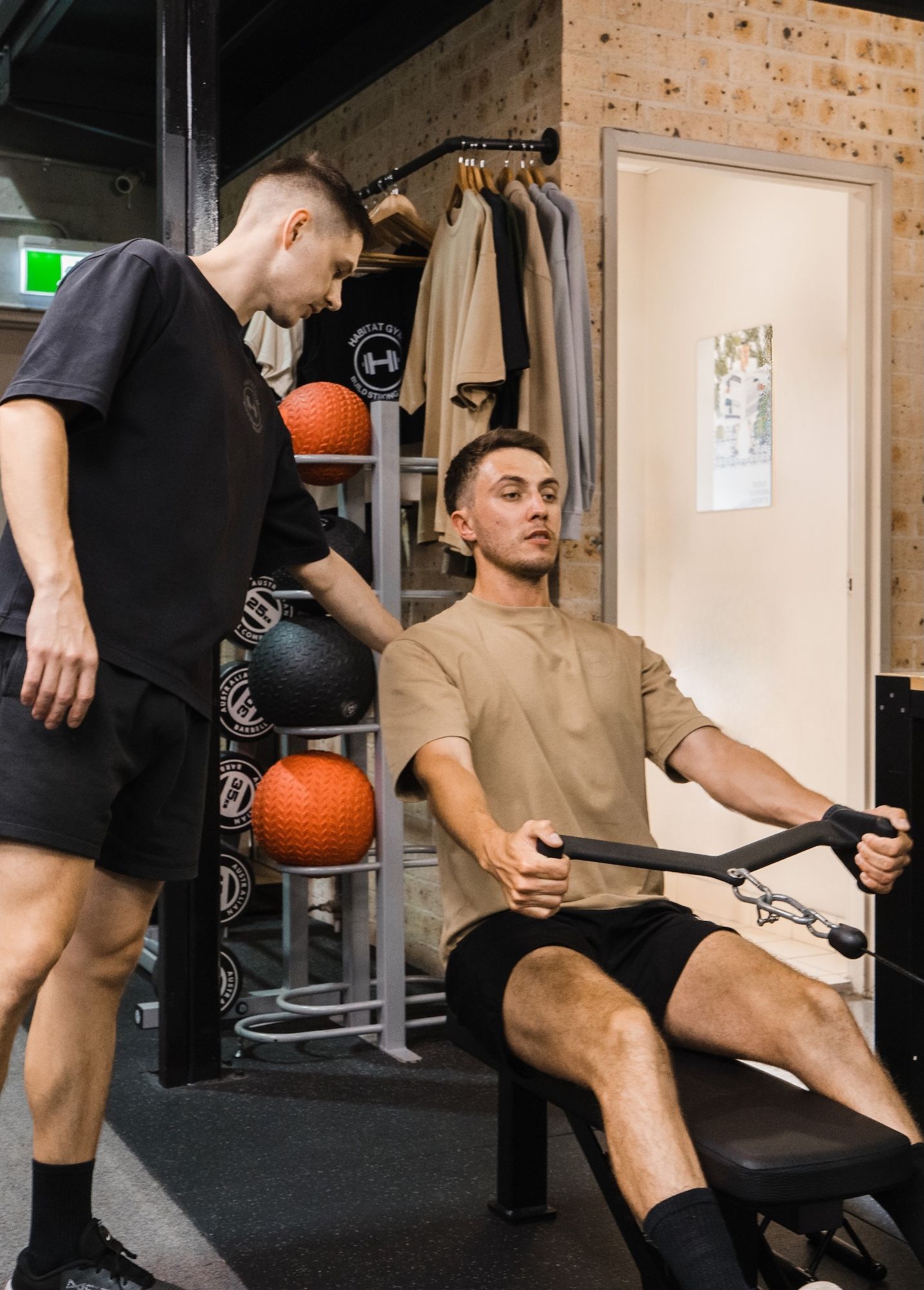 Habitat Gym personal trainer reviewing member's form on assisted weight machine during one-on-one PT session