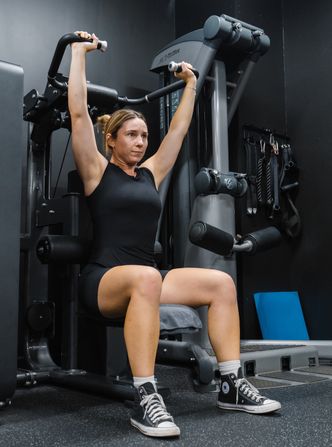 Female gym member training on shoulder press machine in Habitat Gym strength zone