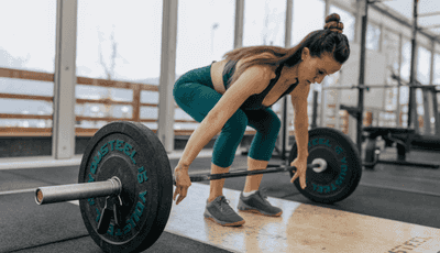 Woman lifting barbell inside a gym during strength training workout